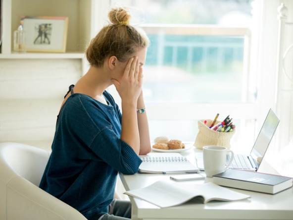 Woman holding head while seated at desk